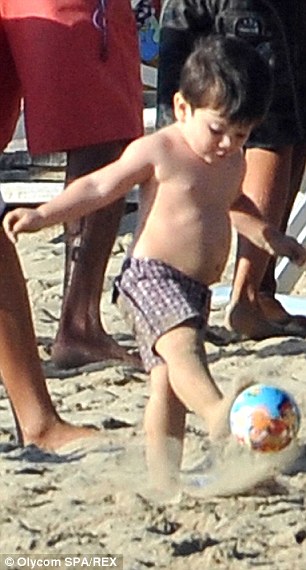 Skills: The adorable tot appears to be in his element as he kicks the ball around the sandy shores