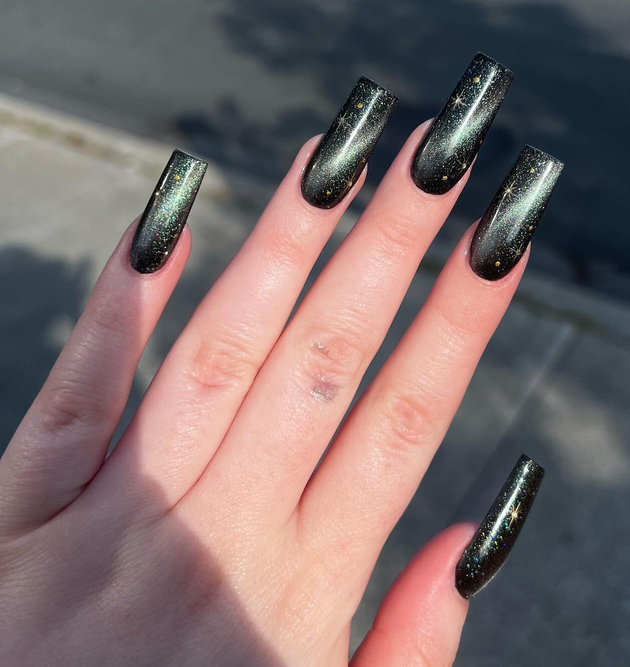 Black galaxy-inspired nail art on long square nails