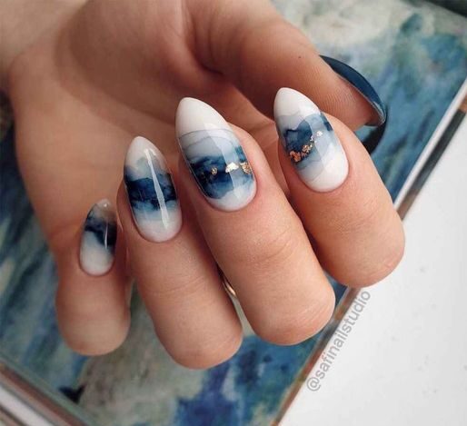 Clean white nail color with blue marbled galaxy nail design on medium almond nails