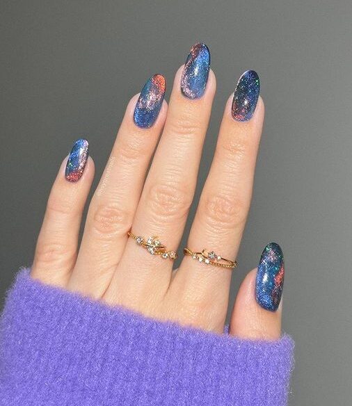 Metallic blue galaxy-inspired nail art on medium round nails