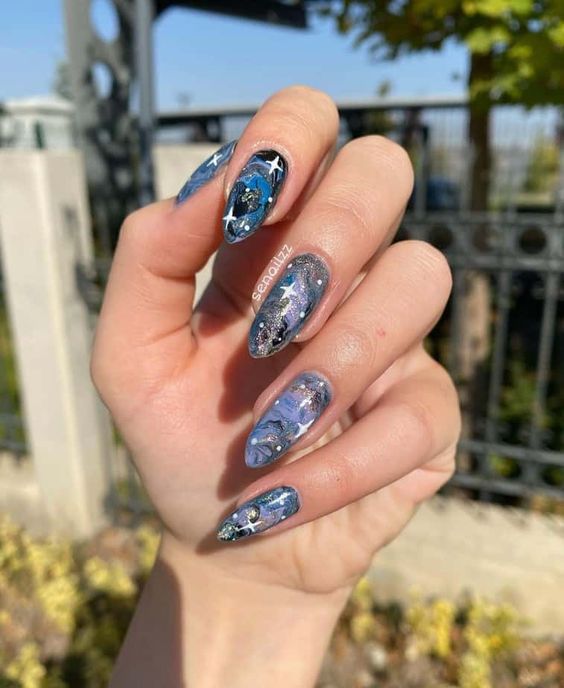 Blue vast galaxy-inspired nail arts on long almond nails