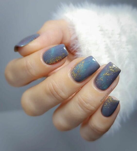 Pale blue nail polish with glitters and gold foil accents on short square nails