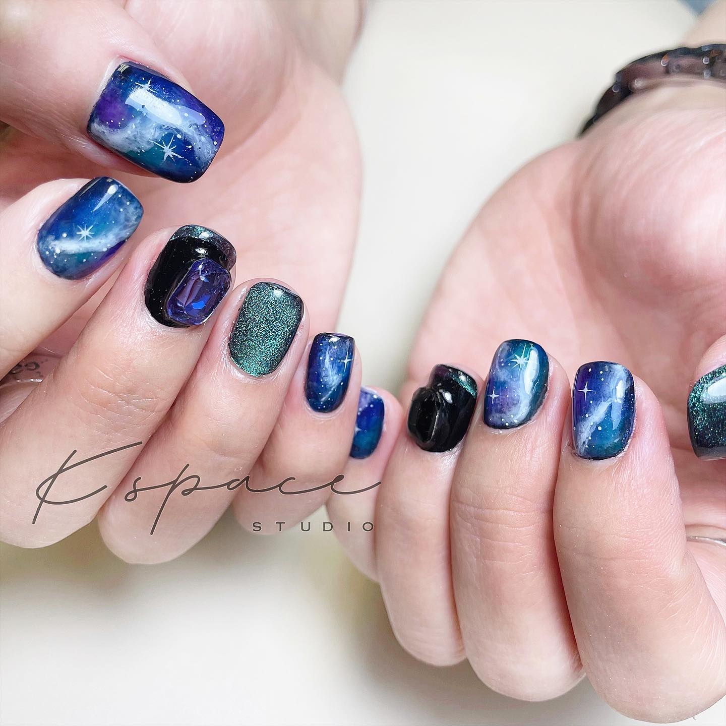 Blue and green nail colors with galaxy-inspired nail art on short tapered square nails