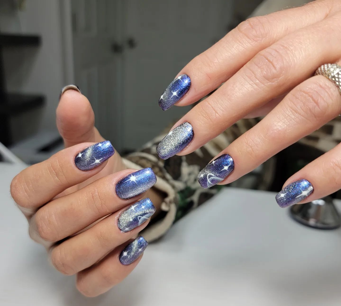 Blue nail color with shimmering galaxy-themed nail design on long tapered square nails