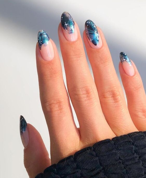 Blue galaxy-themed French tips on long round acrylic nails