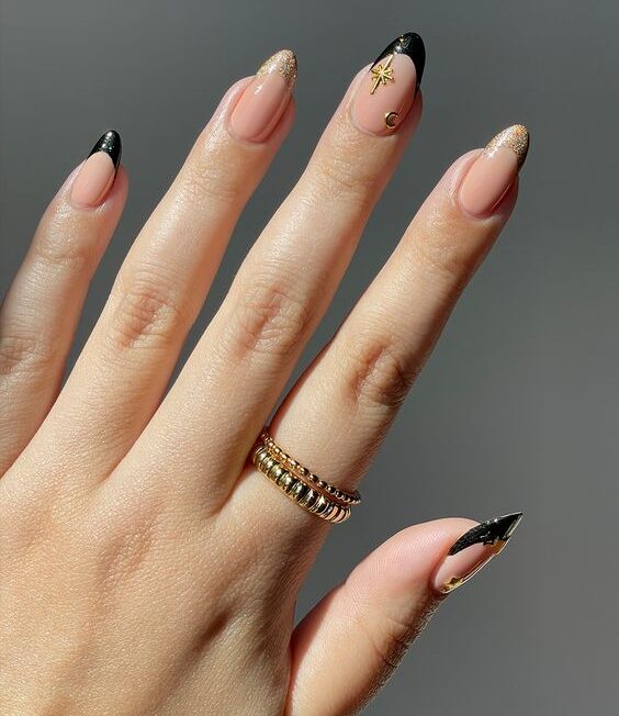 Black and gold French tips with gold celestial elements nail arts on medium round nails