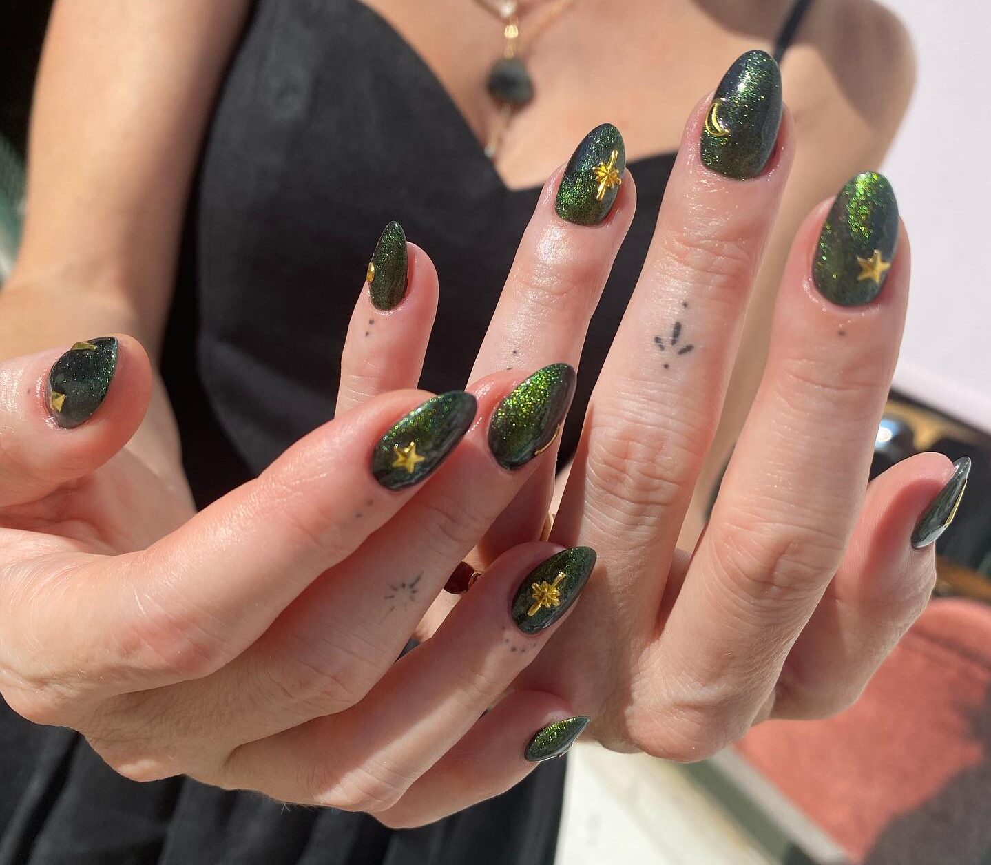 Shining green nail polish with gold celestial elements nail designs on medium round nails