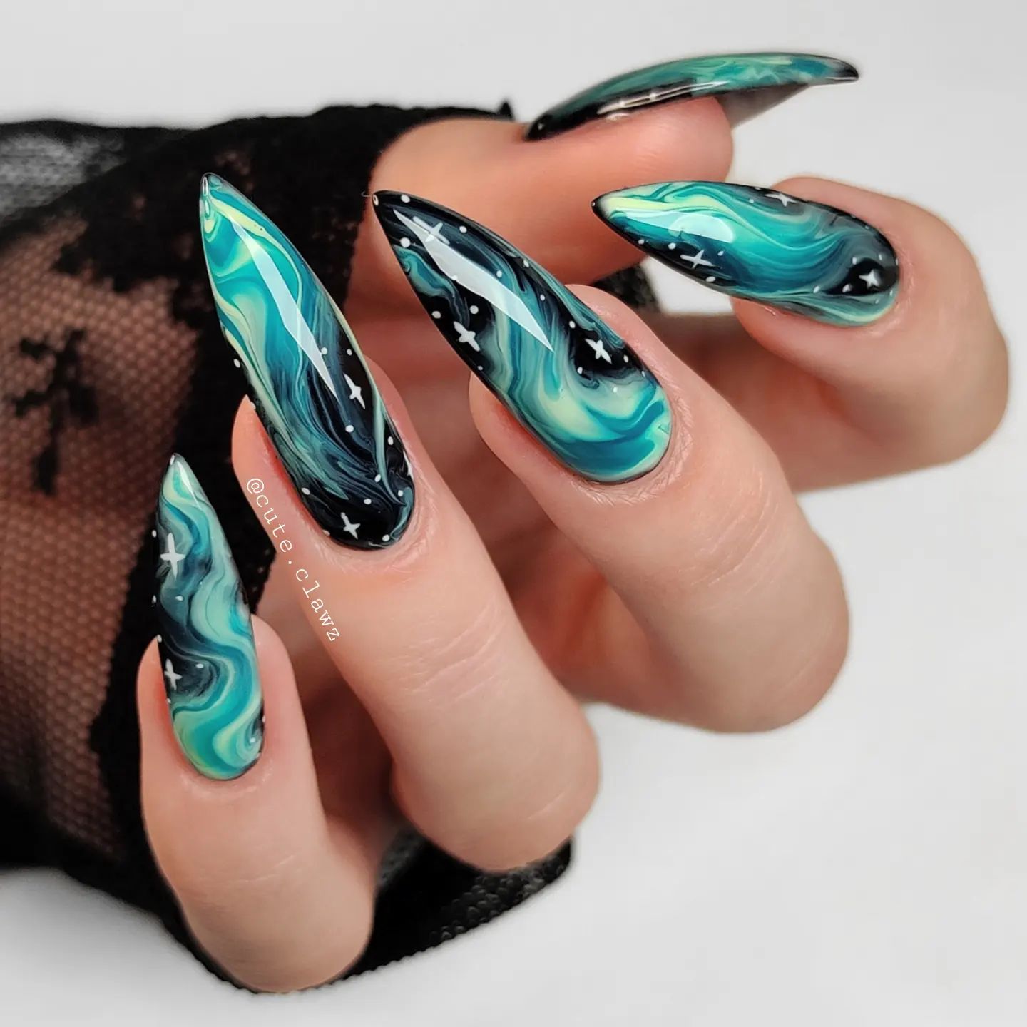 Black and green marbled galaxy nail art in glossy finish on long stiletto shaped acrylic nails