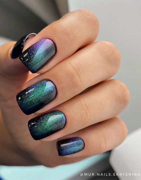 Shimmering black and green galaxy-inspired nail art on medium square nails