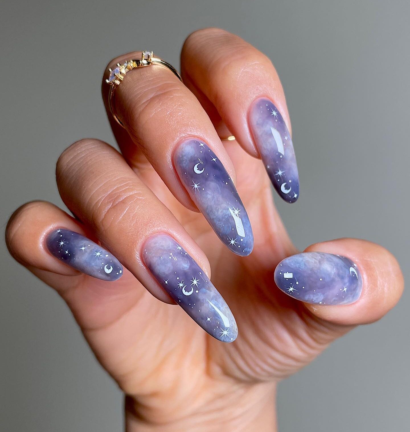 Grayish blue galaxy-themed nail design on long almond nails