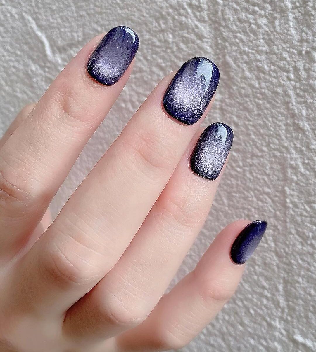 Holographic blue galaxy-inspired nail art on short round nails