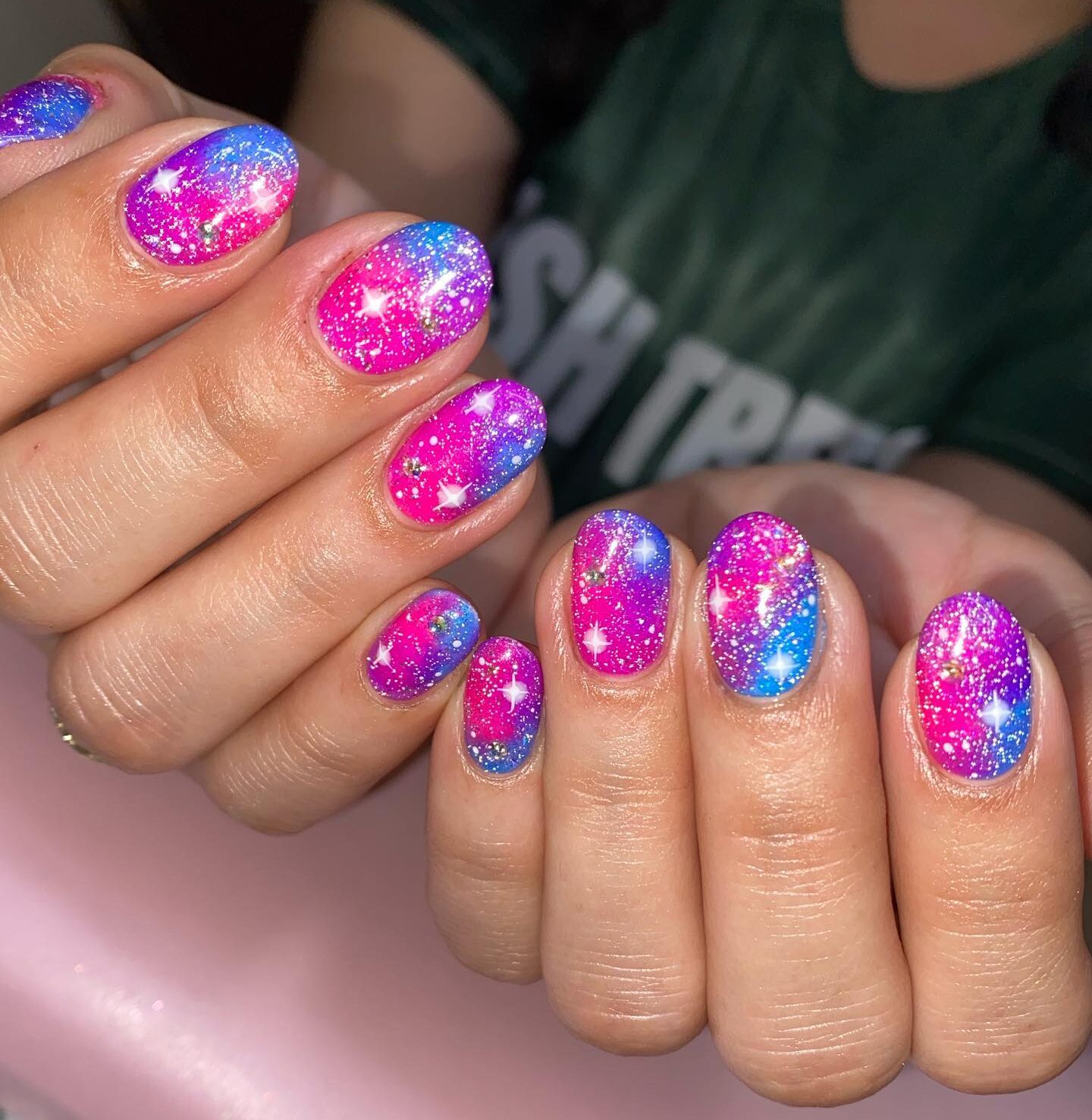 Vibrant pink and blue galaxy-themed nail design on short round nails