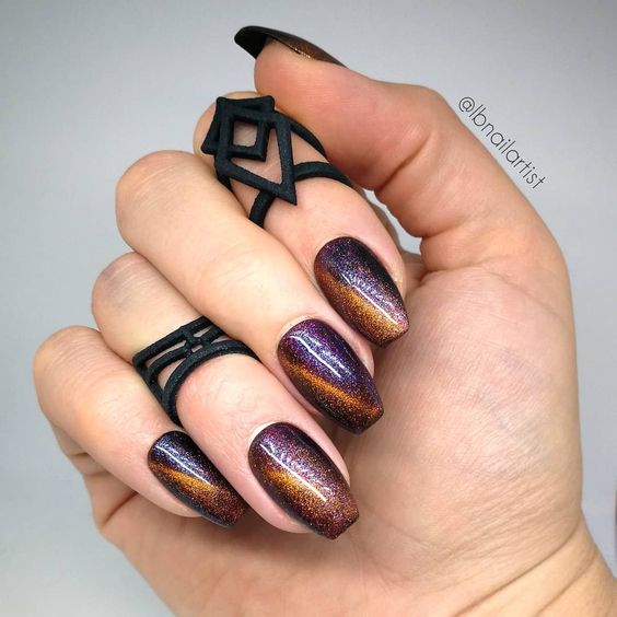 Purple and gold galaxy-inspired nail art on medium coffin nails