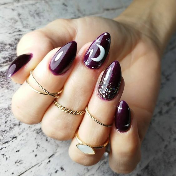 Purple nail polish with glitters and celestial elements nail designs on medium almond nails