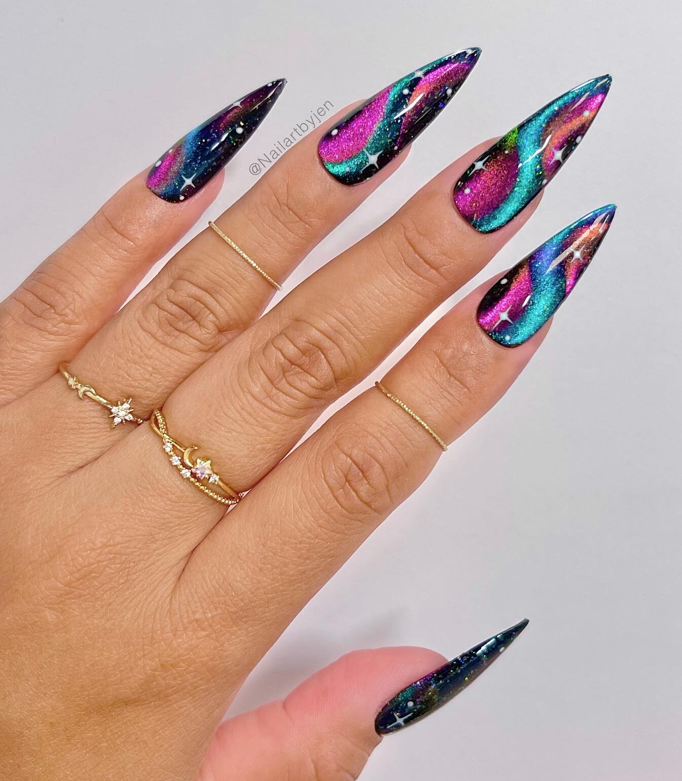 Metallic purple and blue galaxy-inspired swirls on long stiletto nails