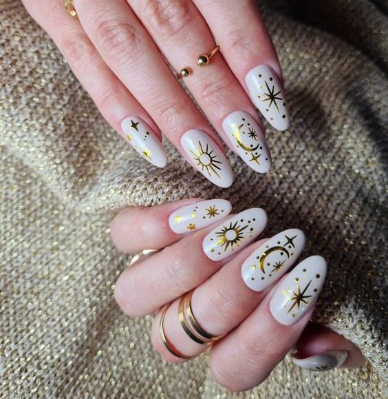 White nail color with gold celestial elements nail designs on long round nails