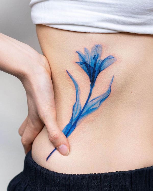 Blue flower side waist tattoo by @pokhy_tattoo