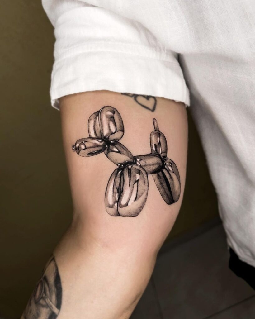 Chrome tattoo of a balloon dog on the inside of a client's bicep.