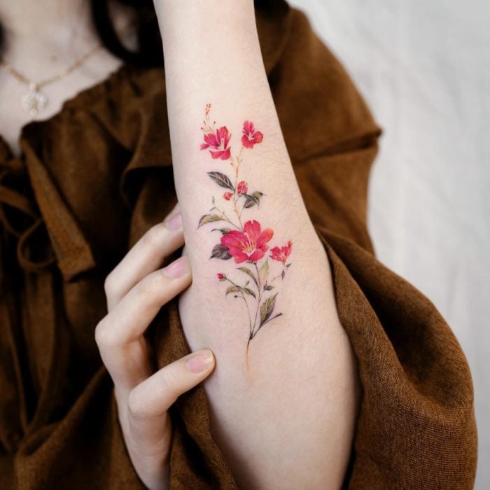 Mini, small tattoo of red feminine flowers on the forearm