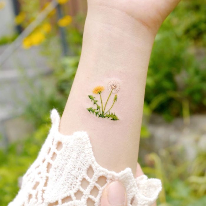 Mini, small tattoo of white and yellow feminine flowers, dandelions on the arm