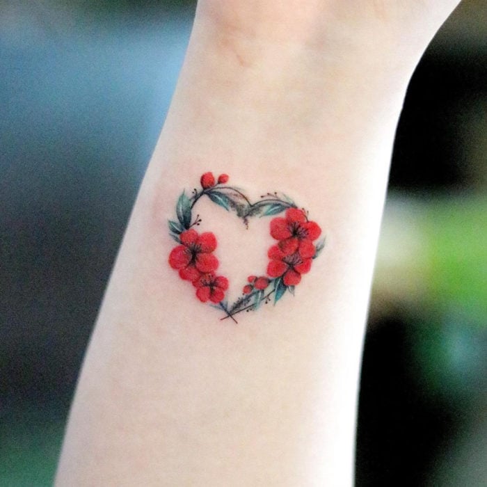 Mini, small tattoo of red feminine flowers forming a heart on the wrist