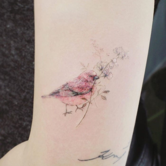 Mini, small tattoo of white feminine flowers with a bird on the arm