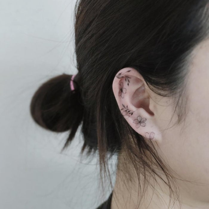 Mini, small tattoo of feminine flowers on the ear