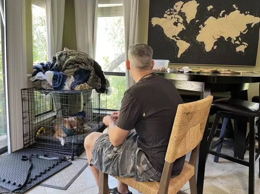 man sitting on a chair next to kennel